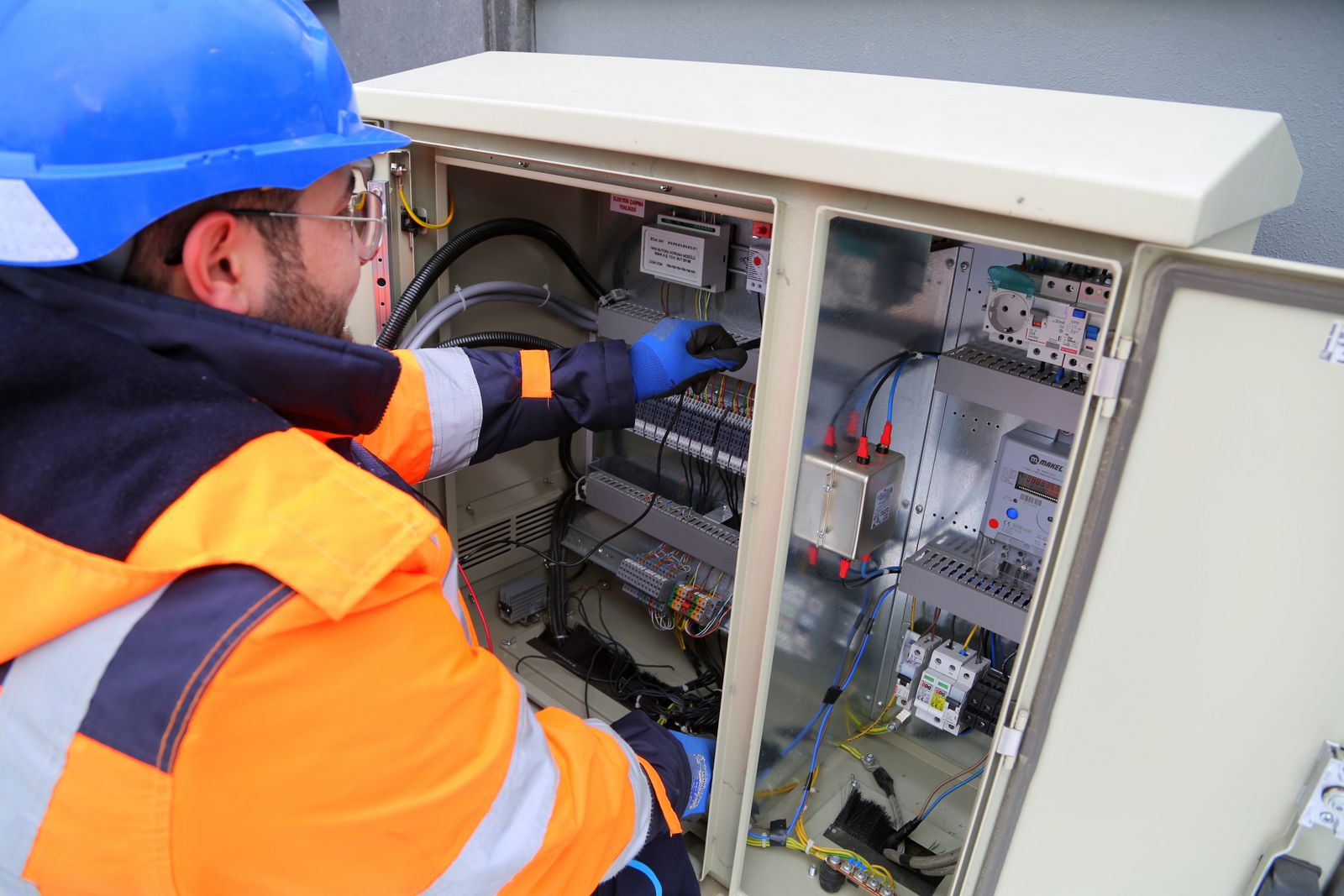 Technicien en équipement de protection devant une armoire électrique