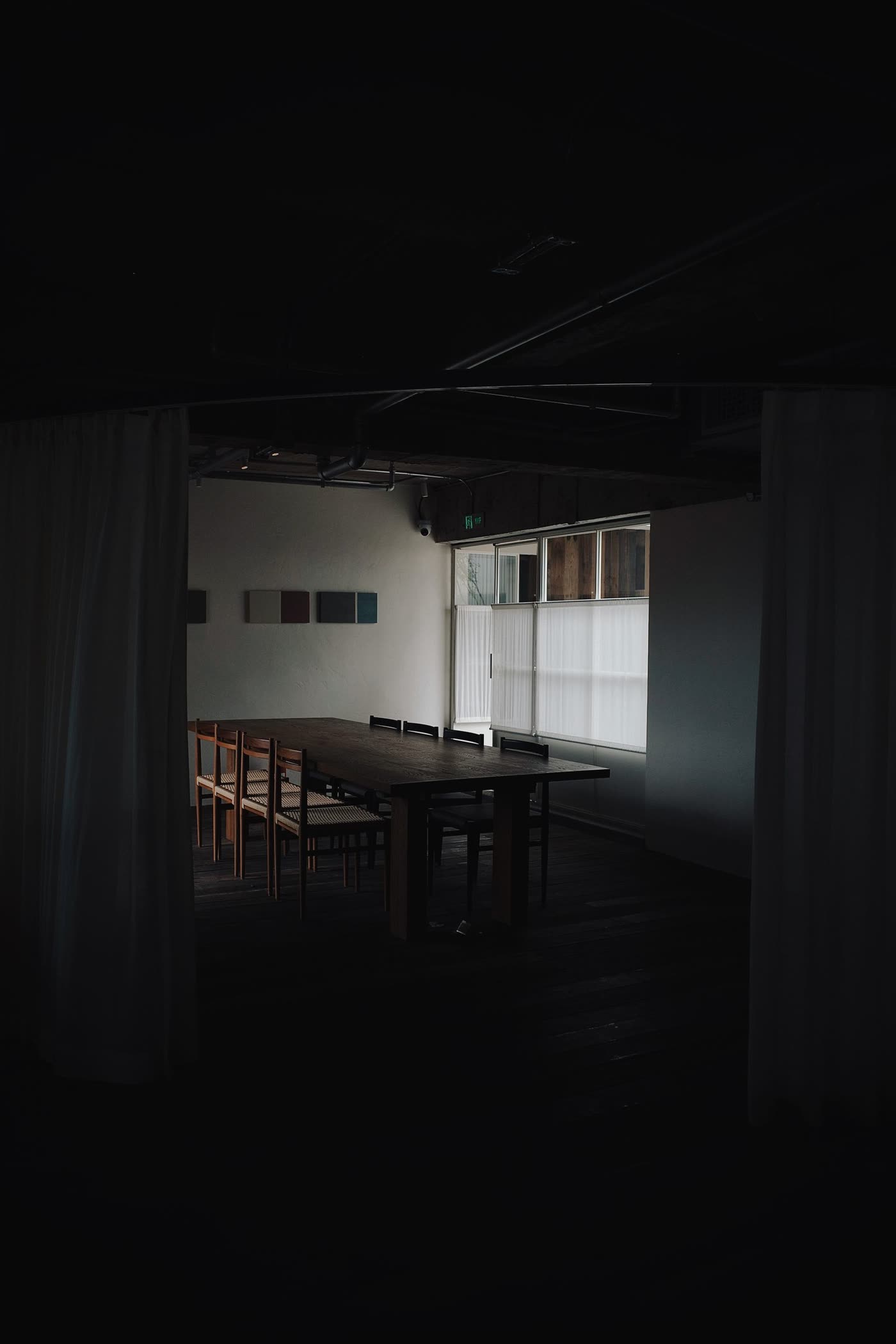 Salle à manger sombre, grande table et lumière rasante