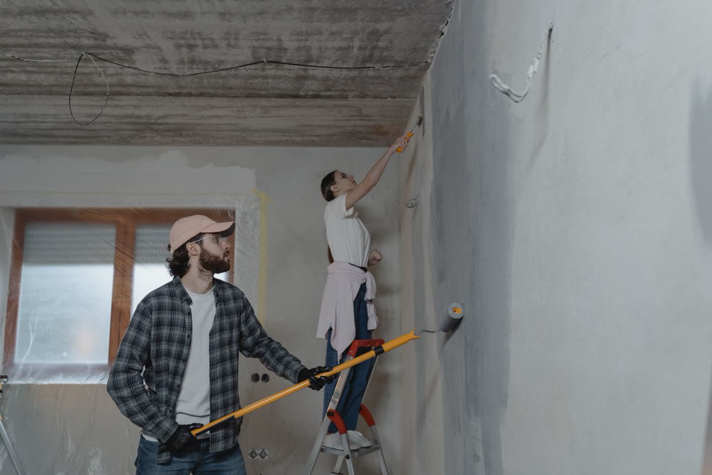 Deux artisans en train de reprendre un plafond à l'enduit